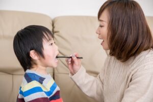 お母さんに仕上げ磨きをしてもらう男の子